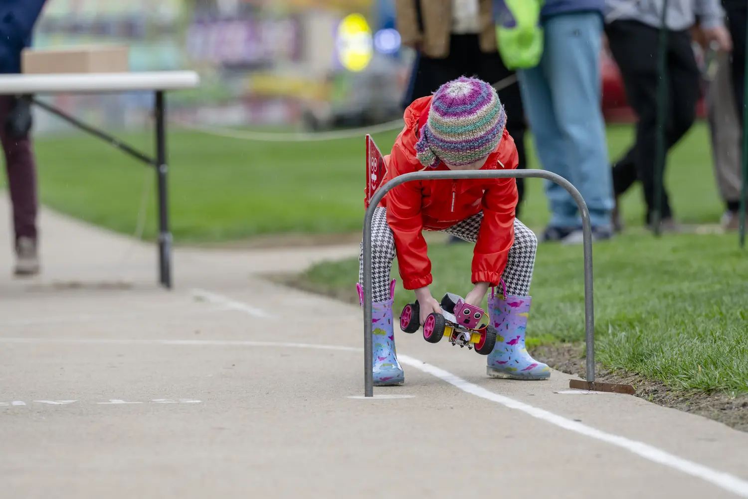 Little girl puts a pink smiley mini robot onto the Mobot course.