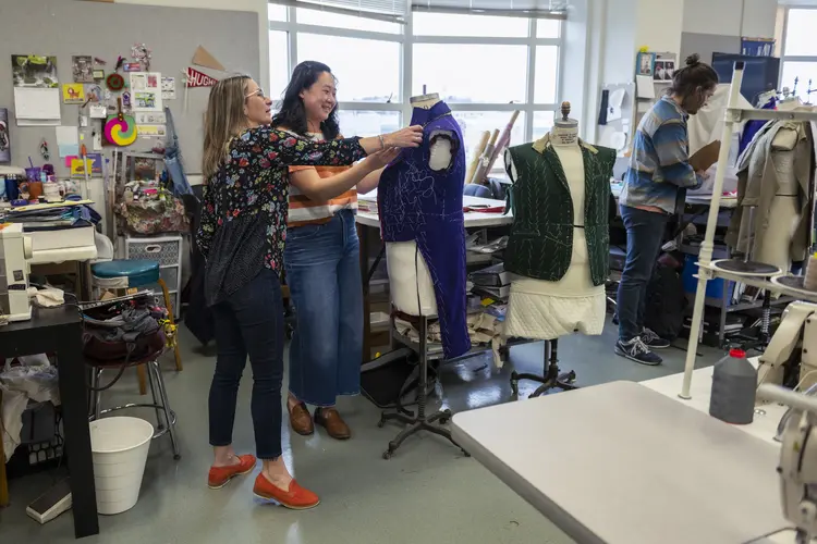 Tiia Lager helping student adjust blue costume on mannequin torso