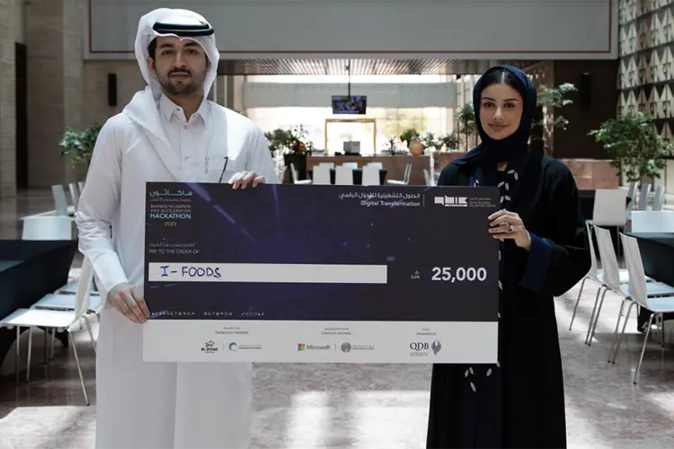 Two Qatar students holding large check