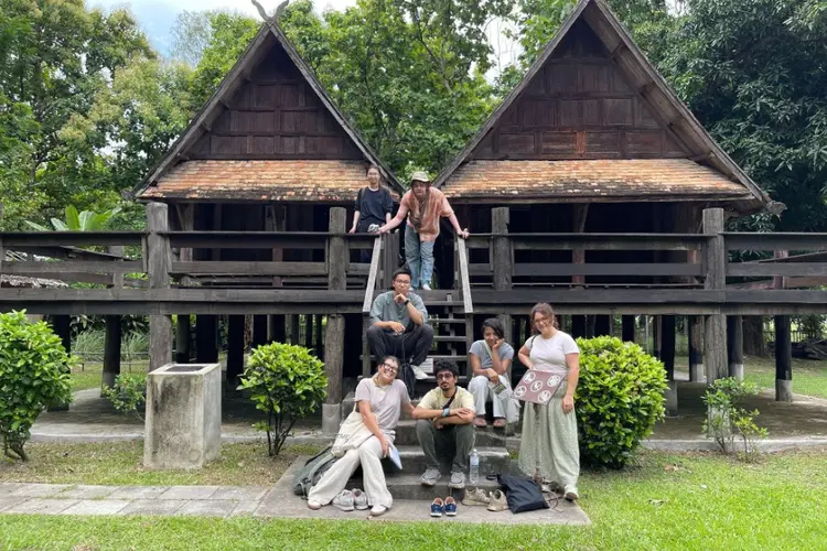 students pose on steps in front of adjoined huts