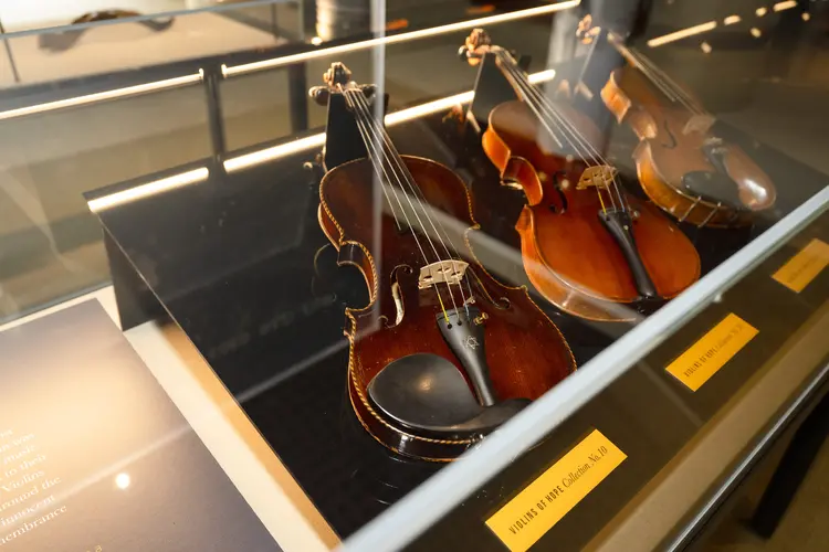 three violins displayed inside a clear case