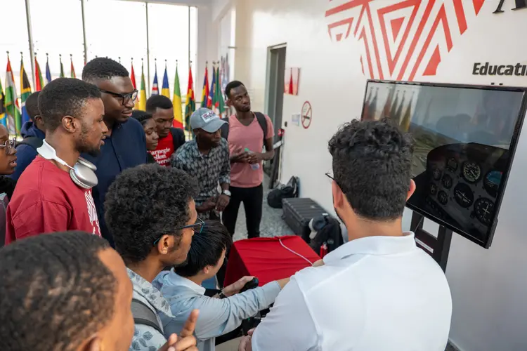 students gathered around a flight simulator demo