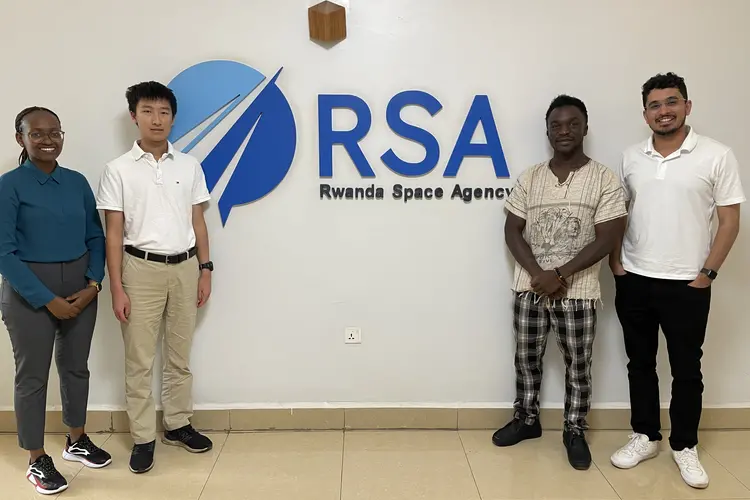 four people standing in front of wall featuring Rwanda Space Agency logo