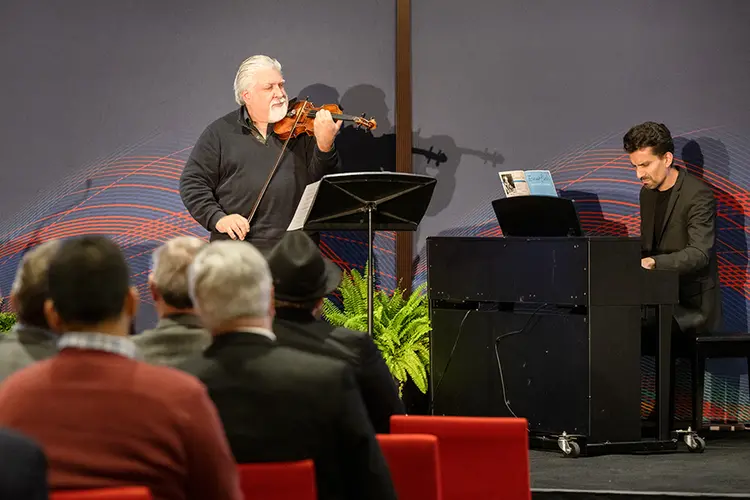 Andrés Cárdenes plays violin on stage accompanied by pianist