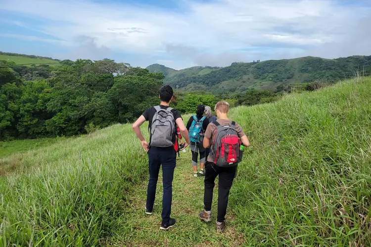 People walking on a green hill's path in Costa Rica.