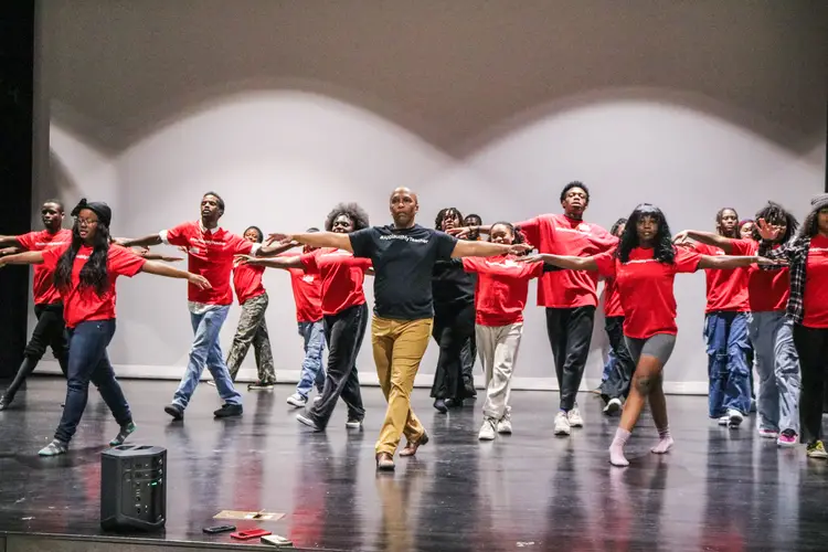A line of dancers in red shirts. 