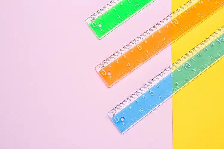 three plastic rules placed diagonally on a pink and yellow background