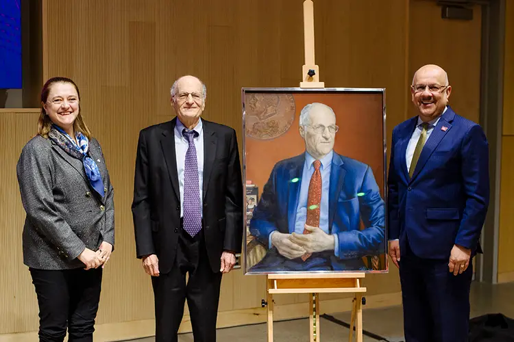 Noebl Laureate Thomas J. Sargent stands with a painted portrait of himself, with Tepper Dean Isabelle Bajeux-Besnainou standing on his left and CMU President Farnam Jahanian standing to the right of the portrait