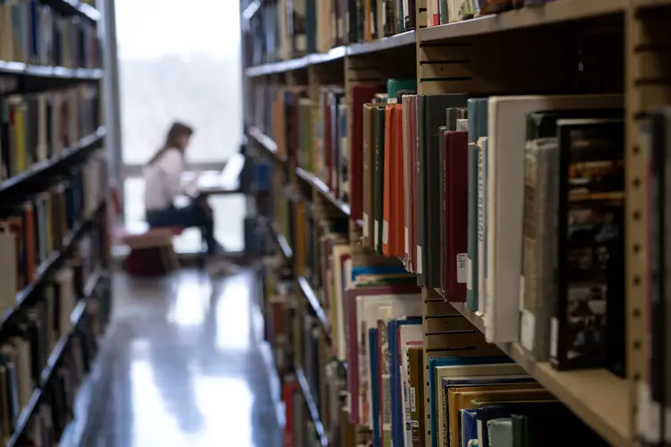 A student reading inside a library. 