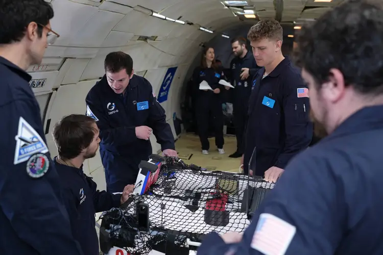 A group of people in blue suits perform tests in zero-G.