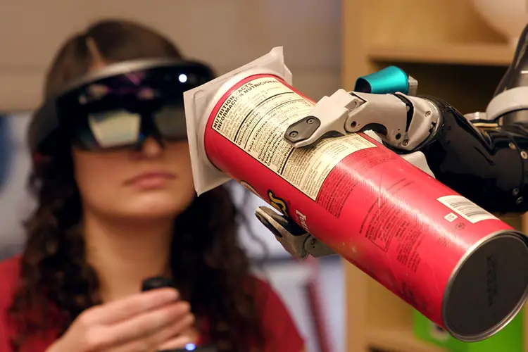 A robotic arm hands a Pringles can to a person. 