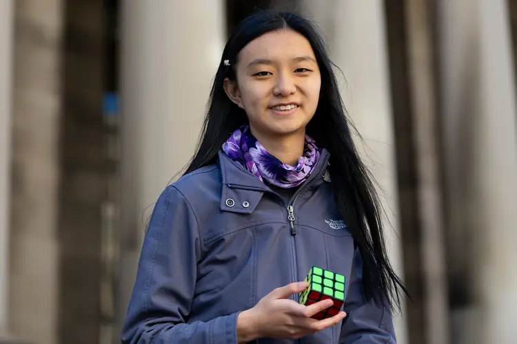 Jenny Quan holds a Rubik's cube in front of the Mellon College of Science building.