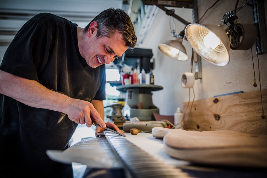 Image of Devon Smullen hand carving a guitar.