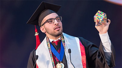 Image of graduation speaker holding a rubiks cube