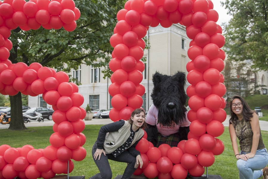 Scotty the mascot poses with students in front of 50th anniversary balloons