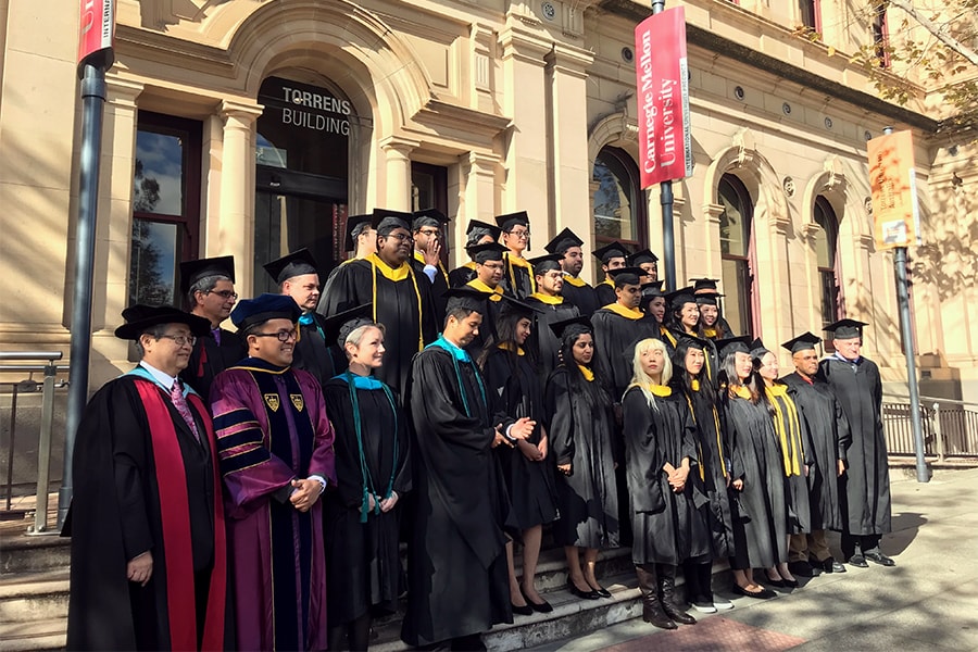 CMU-A graduates stand in front of the Torrens Building