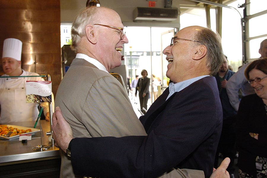 candid image of Bill Elliott at his retirement party hugging and sharing a laugh with Eric Grotzinger 