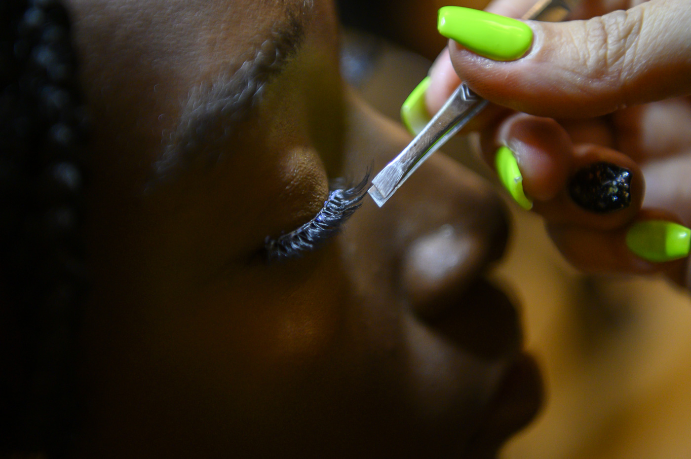 A stylist applies eyelashes to a model.