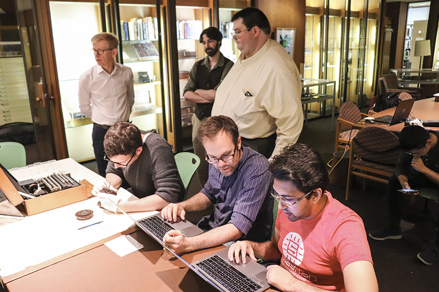 A group gathers around the Enigma machine