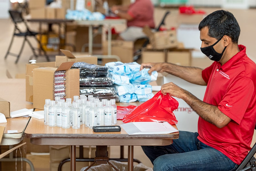 image of male seated at table packing wellness kits items into a red bag