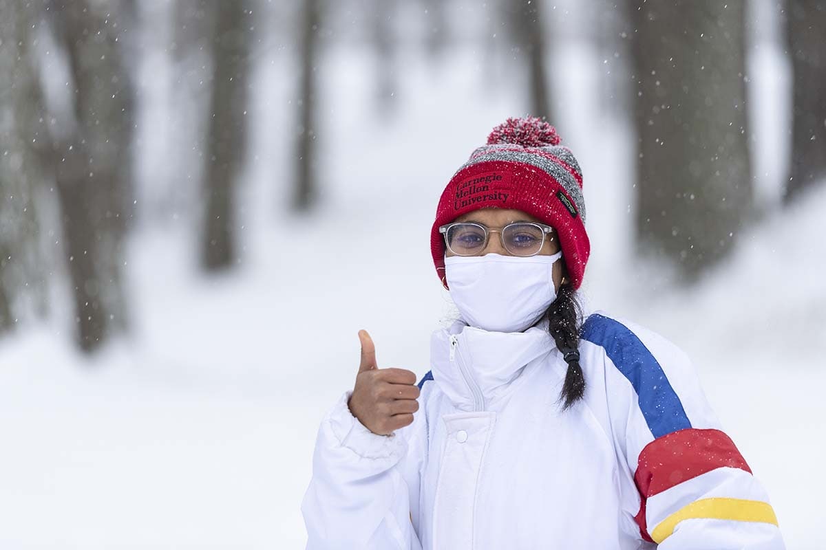 A student gives a thumbs up in the snow.