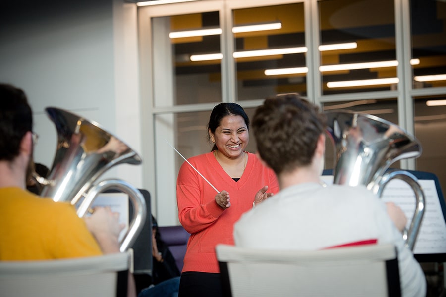 an MBA student smiles while conducting the tuba band