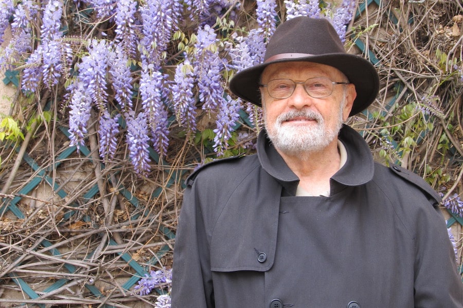 Richard E Young stands in front of purple wisteria