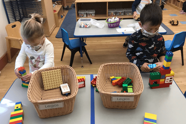 children wearing masks playing with Lego blocks