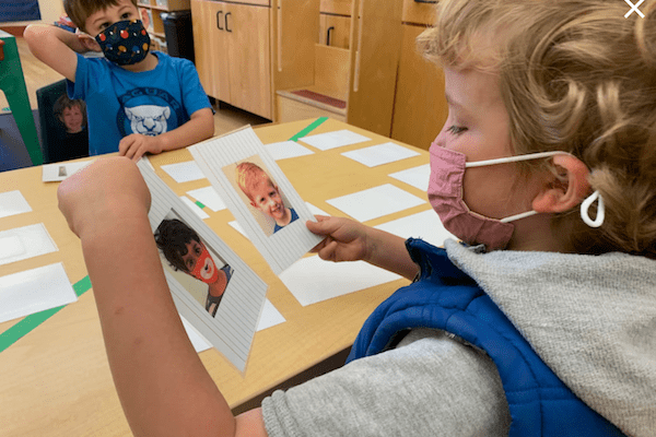 children wearing masks play with face image cards