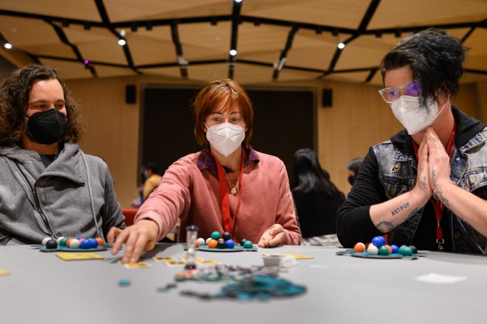 A picture of brainplay conference attendees sitting at a table playing a card game.