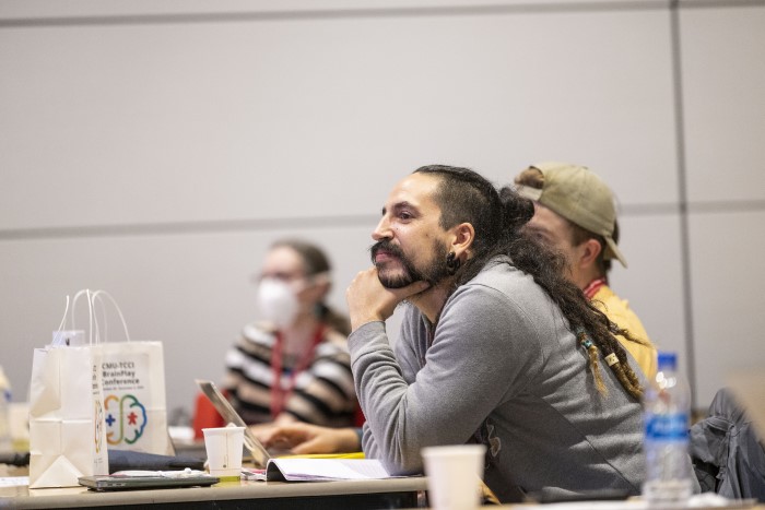 A picture of a brainplay conference attendee listening to a speaker. 