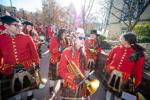 Members of the Kiltie band wearing uniforms and laughing in the sunshine