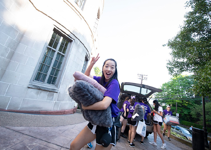 New student moving into dorm giving peace sign with fingers