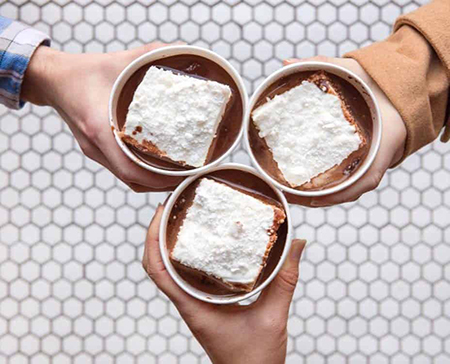 Picture of three hands holding cups of hot chocolate with large marshmallow’s in them
