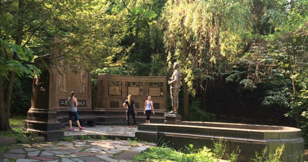 Three runners standing around a statue