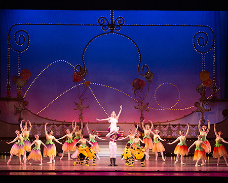 Scene from the Nutcracker with the ensemble cast in the background and the characters performing a lift