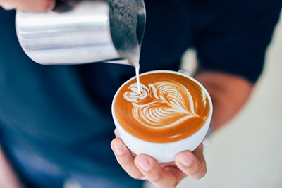 Image of a person pouring milk into coffee and making latte art