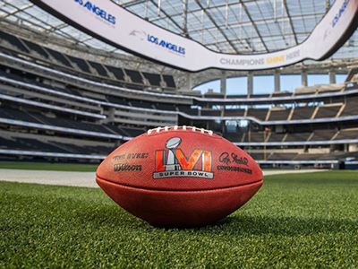 Image with of a football on a field with the Superbowl logo on it
