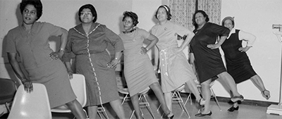 Black and white photo of women doing chair yoga