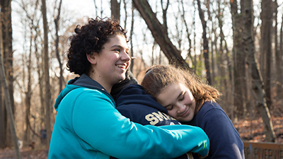 Three friends hugging outdoors