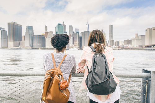 Students overlooking New York City skyline with backpacks on