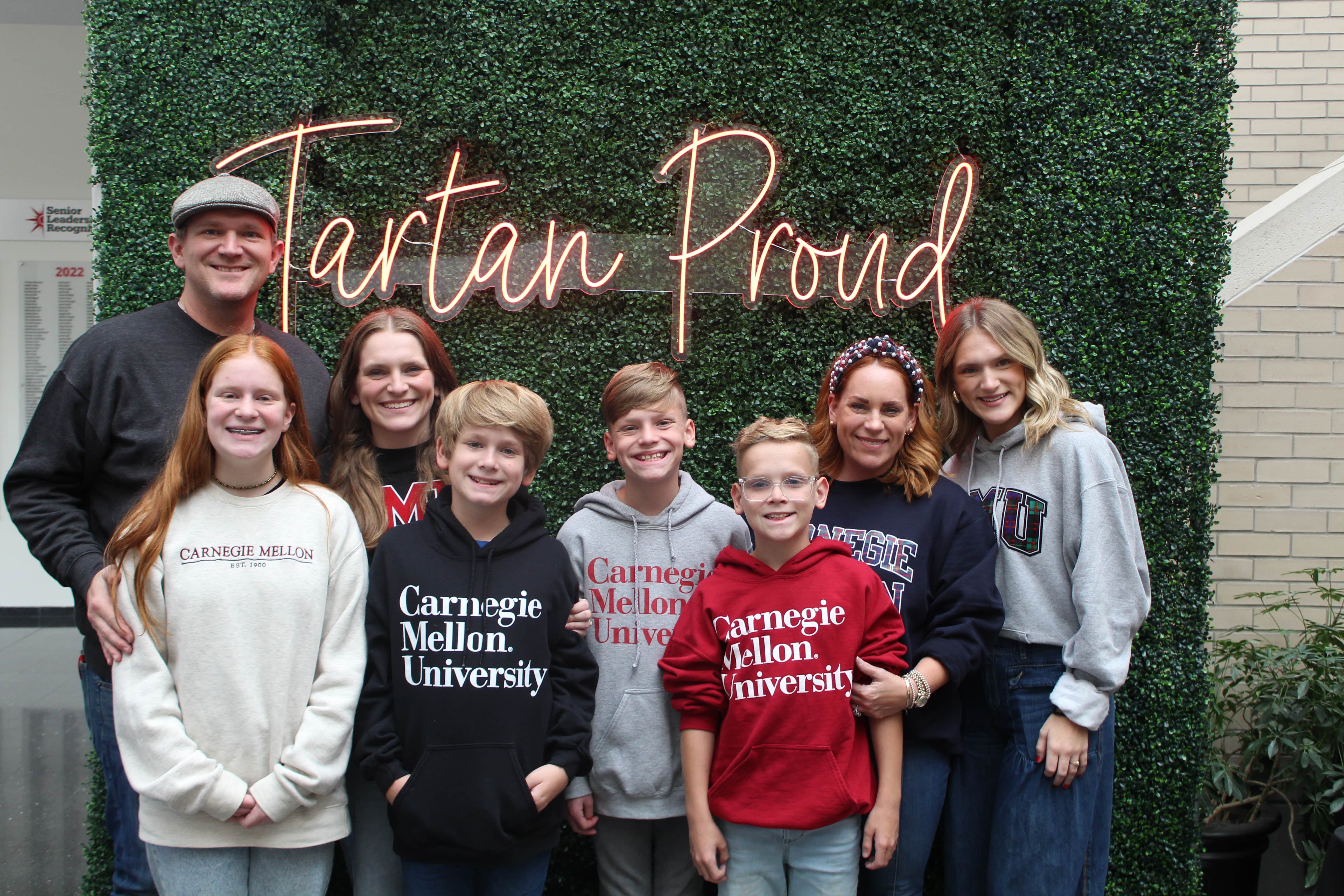 a group of CMU family members standing in front of a Tartan Proud sign