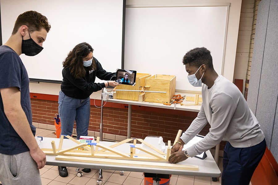 three students in a classroom doing hands on work