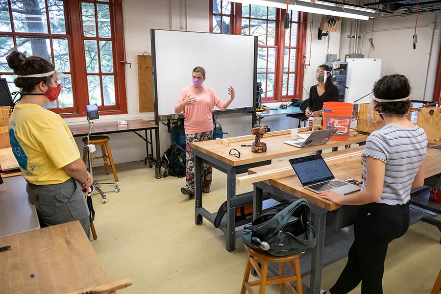 students in a classroom physically distanced and listening to the professor