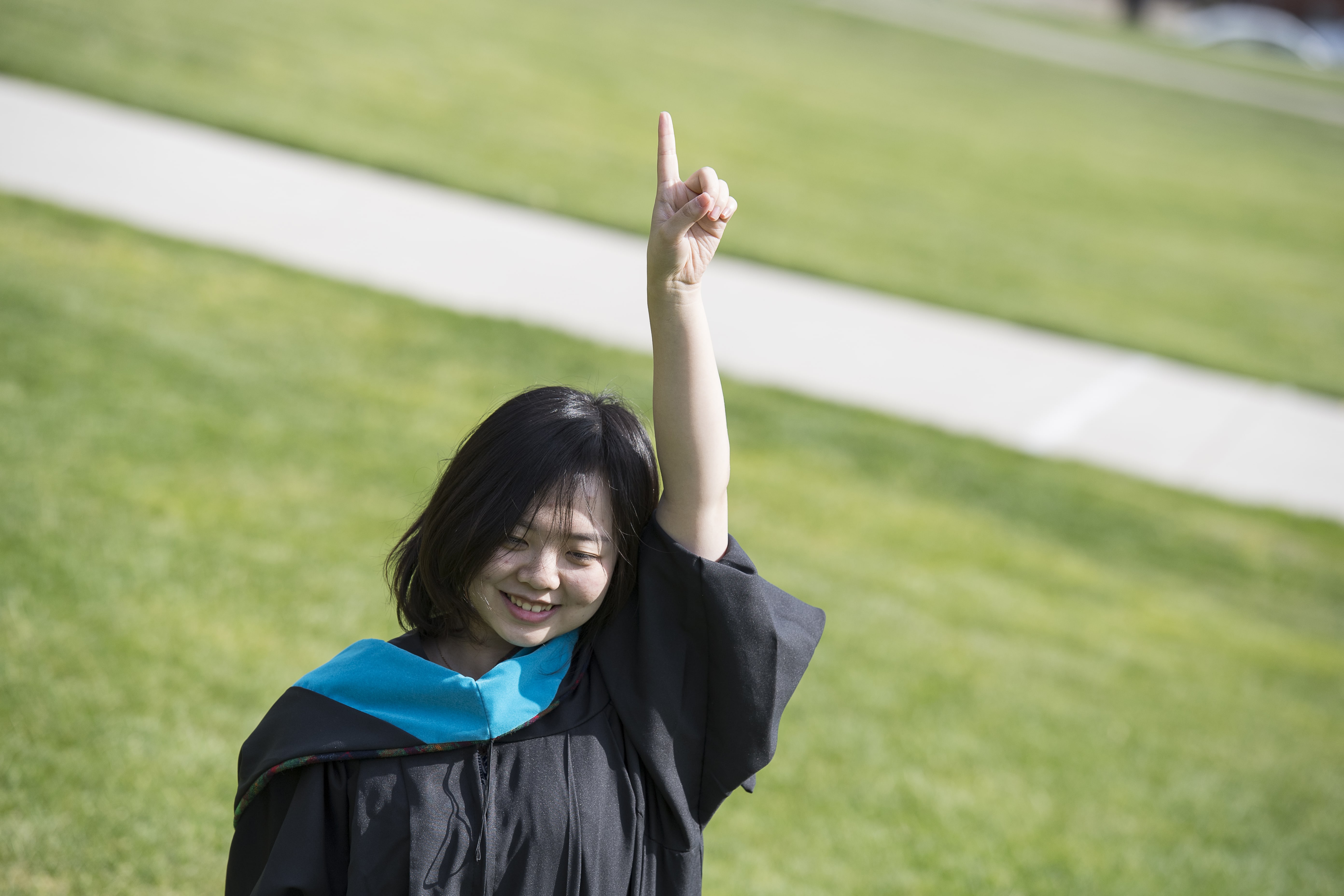 student on graduation day raising her arm in the air 