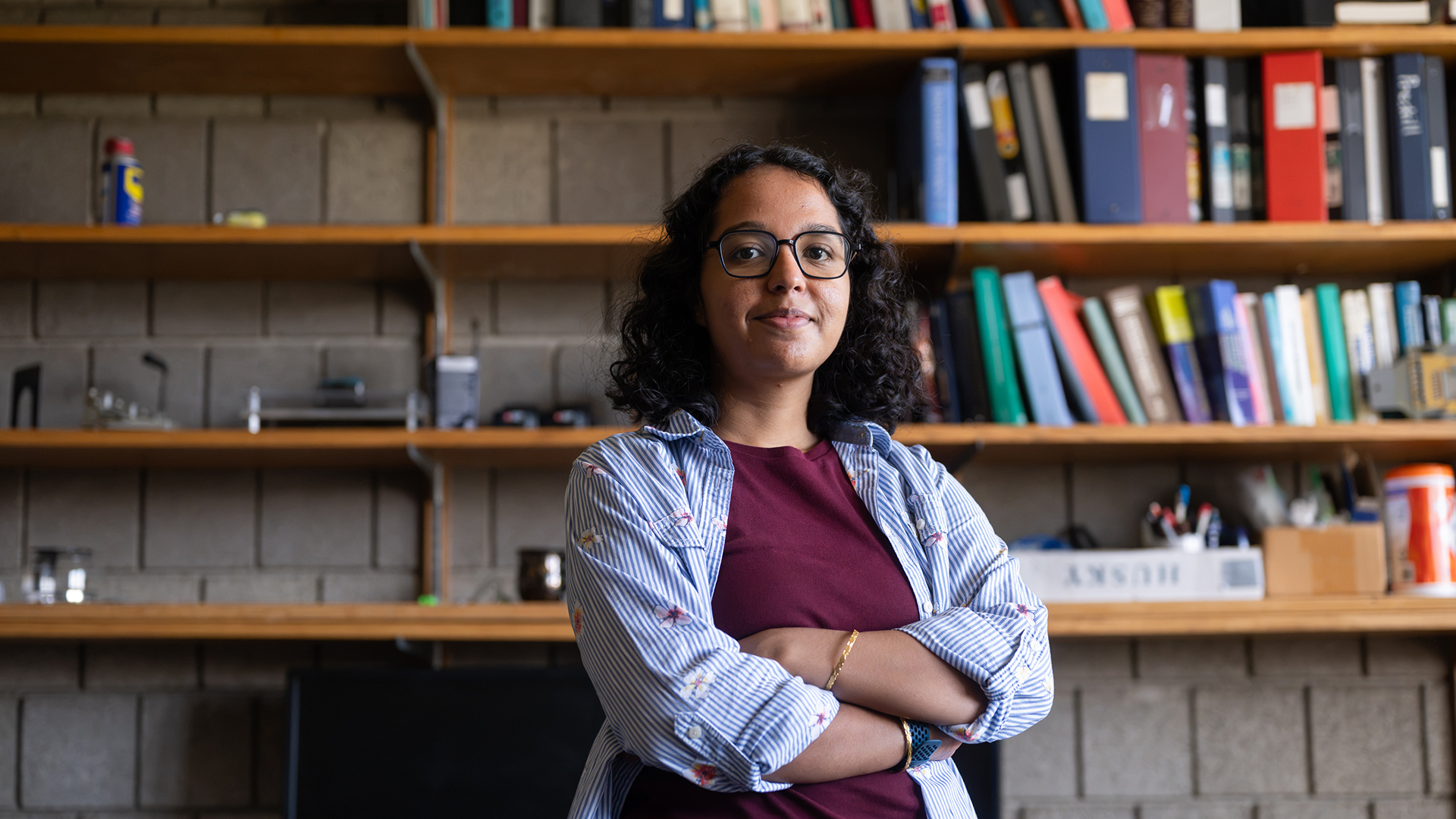 Sindhu Murthy stands in her office with her arms crossed. She smiles at the camera.