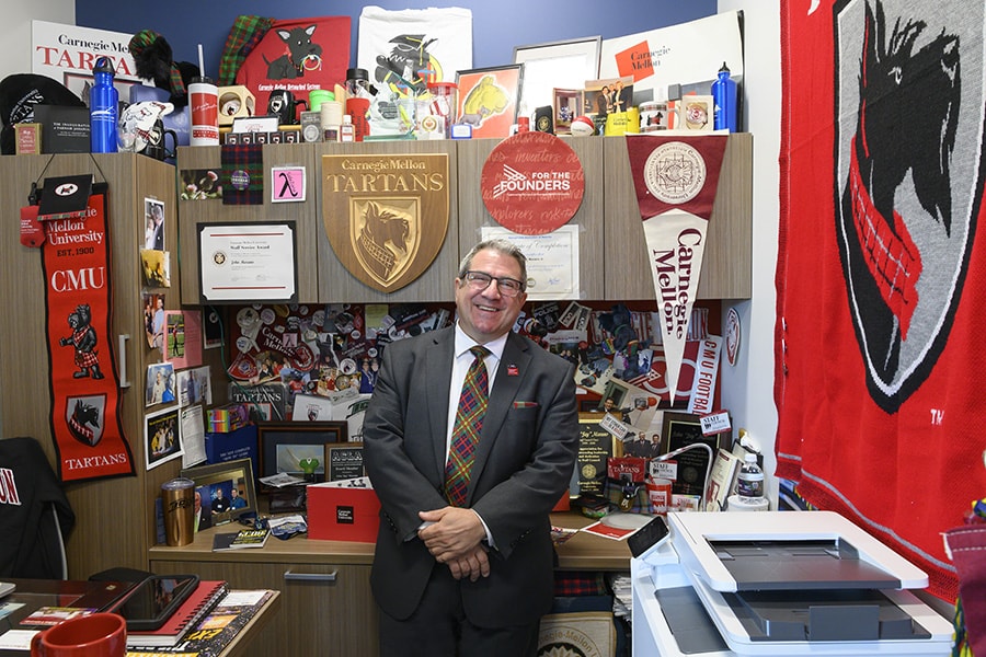 Image of John Marano in his office surrounded by CMU-branded merchandise