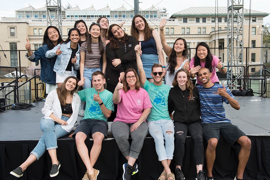 group photo of staff and students on the stage by the tennis courts 