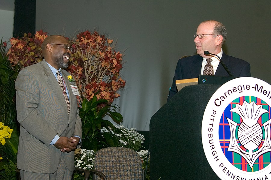 Everett Tademy and Jared Cohon share a friendly glance on stage during a MLK Day celebration 