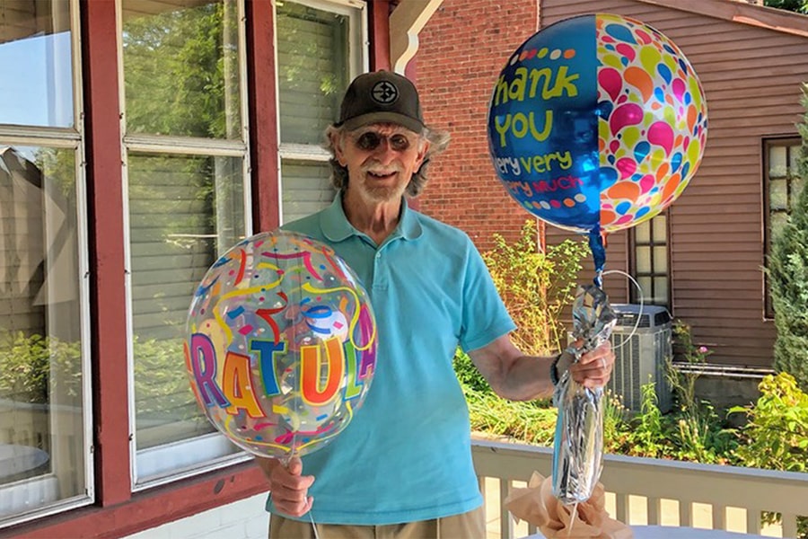David Klahr at home holding congraulatory balloons in honor of his retirement